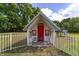 Charming playhouse featuring a red door and white picket fence, perfect for outdoor play at 10575 Sw 27Th Ave, Ocala, FL 34476