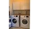 Modern laundry room featuring white front-load washer and dryer and upper cabinets at 10918 Sw 71St Cir, Ocala, FL 34476