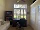 Home office with a large desk, a comfortable chair, and a bookcase filled with books, bathed in natural light at 10918 Sw 71St Cir, Ocala, FL 34476