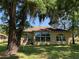 Back of a tan house with a sunroom, visible through large trees with hanging Spanish moss at 10918 Sw 71St Cir, Ocala, FL 34476