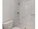Close-up on a toilet and walk-in shower with white marble style tile at 13300 Sw 105Th Pl, Dunnellon, FL 34432