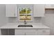 Modern kitchen with white cabinets, granite countertops, and stainless steel sink overlooking the yard at 13300 Sw 105Th Pl, Dunnellon, FL 34432