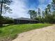 Rear exterior view of the house, showing the simple design, back yard and wooded surroundings at 1475 Sw Big Bear Rdg, Dunnellon, FL 34431
