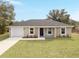 Beautifully landscaped home with a spacious front yard, attached garage, and neutral-toned exterior at 15067 Sw 16 Pl, Ocala, FL 34481