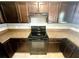 Close-up of a stove, surrounded by granite countertops and dark cabinets, perfect for cooking at 15585 Sw 46Th Cir, Ocala, FL 34473