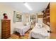 Charming bedroom featuring twin beds, hardwood floors, and a built-in shelving unit for storage at 16405 Se 90Th Ct, Summerfield, FL 34491
