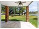 Covered back patio featuring stone pillars, ceiling fan, travertine flooring, and view of backyard with playground at 1718 Sw 27Th St, Ocala, FL 34471