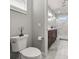 Bathroom featuring a white toilet and brown vanity that leads to the walk-in shower with marble-patterned tiles and hexagon floor tiles at 4020 Se 23Rd St, Ocala, FL 34471