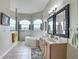 Bright bathroom featuring a dual sink vanity, tiled floors, soaking tub, and arched windows at 4033 Ne 15Th Court Rd, Ocala, FL 34479