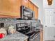 Close up of a modern black range and microwave with granite countertops and warm wood cabinets at 4033 Ne 15Th Court Rd, Ocala, FL 34479