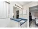 Bright bathroom featuring an expansive mirror, updated vanity with blue countertop, and easy access from the bedroom at 6127 Sw 84Th Place Rd, Ocala, FL 34476