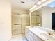 Updated bathroom featuring double sinks, a large mirror, and a glass-enclosed shower with gold trim at 8051 Sw 115 Loop, Ocala, FL 34481