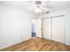 Bedroom featuring sleek wood floors, a ceiling fan, closet, and a door leading to the bathroom at 8051 Sw 115 Loop, Ocala, FL 34481
