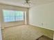 Bright bedroom featuring carpeted floors, a ceiling fan, and a large window bringing in natural light at 8051 Sw 115 Loop, Ocala, FL 34481
