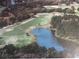 Overhead view showcases a golf course with a scenic pond, surrounded by trees and a residential neighborhood at 8132 Fairways Cir # R103, Ocala, FL 34472