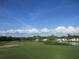Scenic golf course view with green fairways, a lake, and residential housing in the background under a bright blue sky at 8132 Fairways Cir # R103, Ocala, FL 34472