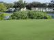 Scenic view of a golf course green with a flag, pond, and houses in the distance at 8132 Fairways Cir # R103, Ocala, FL 34472