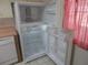 Kitchen featuring a white refrigerator with open doors, and a red and white checkered curtain at 8132 Fairways Cir # R103, Ocala, FL 34472