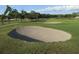 The image shows a well-maintained golf course with a sand trap hazard set amongst lush green grass and mature trees at 8132 Fairways Cir # R103, Ocala, FL 34472