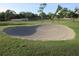 The image shows a sand trap hazard on a well-maintained golf course with lush green grass and mature trees at 8132 Fairways Cir # R103, Ocala, FL 34472