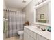 Bright bathroom with white vanity, decorative mirror, and bathtub with a patterned gray shower curtain at 8625 Sw 94Th Ln # D, Ocala, FL 34481