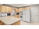 Well-lit kitchen with wood cabinets, white appliances, tile flooring, and a functional layout for efficient cooking at 8625 Sw 94Th Ln # D, Ocala, FL 34481
