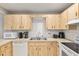 Compact kitchen with light wood cabinets, white appliances, and a practical layout for easy meal preparation at 8625 Sw 94Th Ln # D, Ocala, FL 34481
