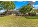 A sunny exterior view of a home with mature trees and a green lawn, showcasing its curb appeal at 8750 Sw 108Th St, Ocala, FL 34481
