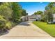 Wide view of the house exterior with a long driveway and lush landscaping on a sunny day at 8750 Sw 108Th St, Ocala, FL 34481
