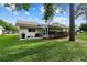 Exterior view of the home's backyard with green grass, mature trees, and a patio area with a grill at 8833 Sw 98Th Street Rd # E, Ocala, FL 34481