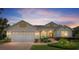 Inviting single-story home showcasing manicured landscaping, a brick driveway, and a two-car garage as dusk settles at 8904 Sw 84Th Cir, Ocala, FL 34481