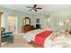 Bright main bedroom featuring neutral carpet, ceiling fan and views into the main bathroom at 8904 Sw 84Th Cir, Ocala, FL 34481