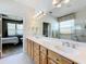 Bright bathroom with double vanity, lots of storage, and doorway to bedroom with carpet and bed at 9347 Se 137Th Street Rd, Summerfield, FL 34491