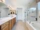 Bathroom featuring a glass-enclosed shower, soaking tub, and dual sink vanity at 9347 Se 137Th Street Rd, Summerfield, FL 34491