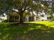 Home exterior with large tree providing shade, manicured lawn and shrubs at 9347 Se 137Th Street Rd, Summerfield, FL 34491