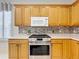 Kitchen with stainless steel oven and stovetop and oak cabinets with white countertop at 9347 Se 137Th Street Rd, Summerfield, FL 34491