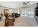 Spacious living room offers carpet flooring, a ceiling fan, and sliding glass doors to the sunroom at 9347 Se 137Th Street Rd, Summerfield, FL 34491