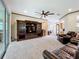 Open-concept living room with ceiling fan, carpet flooring, and a dark wood entertainment center at 9347 Se 137Th Street Rd, Summerfield, FL 34491