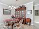 Dining room with a chandelier, china cabinet, and a glass-top table set for four at 9740 Sw 68Th Ln, Ocala, FL 34481