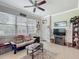 Cozy living room features a ceiling fan, decorative fireplace and large windows with natural light at 9740 Sw 68Th Ln, Ocala, FL 34481