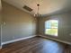 Bright dining room showcasing a chandelier, hardwood floors, a large window, and neutral paint at 9934 Se 64Th Ave, Belleview, FL 34420