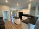 A kitchen featuring granite countertops, white cabinets, black appliances, and an island with wood-look flooring at 9934 Se 64Th Ave, Belleview, FL 34420