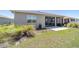 Backyard view with a lush green lawn, landscaping, and an enclosed lanai with an adjacent concrete patio at 10033 Sw 96Th St, Ocala, FL 34481
