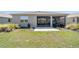 Backyard view with a lush green lawn, landscaping, and an enclosed lanai with an adjacent concrete patio at 10033 Sw 96Th St, Ocala, FL 34481
