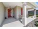 Cozy front porch featuring a red front door, seating area, and stylish columns at 10033 Sw 96Th St, Ocala, FL 34481