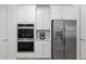 Gourmet kitchen with stainless steel appliances, including a double oven and a refrigerator, set against sleek white cabinetry at 1119 Se 42Nd Rd, Ocala, FL 34480