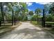 A long driveway leads to a home, framed by an ornate iron gate and lush trees at 11311 Ne 40Th Street Rd, Silver Springs, FL 34488