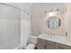 Bathroom with a shower-tub, wooden cabinets, and a round mirror over the sink at 1251 Sw 43Rd Pl, Ocala, FL 34471
