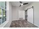 Bedroom featuring wood-look floors, a ceiling fan, a barn door closet and natural light from a large window at 14115 Nw 141St Ave, Williston, FL 32696