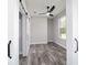 Bedroom featuring wood-look floors, a ceiling fan, a barn door closet and natural light from a large window at 14115 Nw 141St Ave, Williston, FL 32696